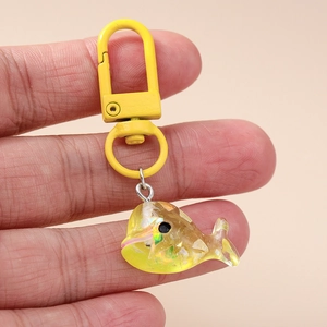 Gros plan d'un porte-clés baleine en résine jaune avec paillettes et fermoir mousqueton