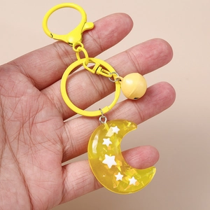 Yellow moon and star resin keychain with bell and lobster clasp held in hand