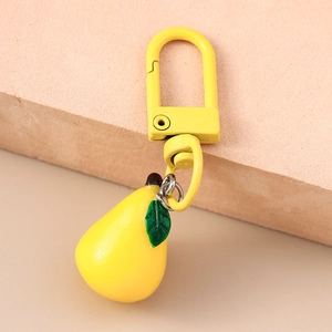 Close-up of yellow pear fruit keychain with green leaf and matching metal hook