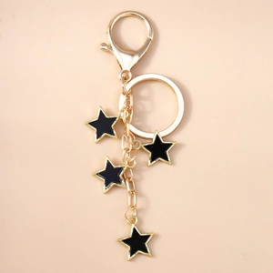 Détail du porte-clés étoile dorée avec pendentifs en émail noir et fermoir mousqueton