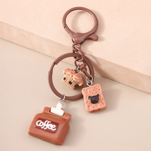 Detail view of coffee and cake charms on a brown metal keychain with bear pattern
