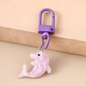 Détail d'un porte-clés dauphin en résine violette avec paillettes et crochet en métal