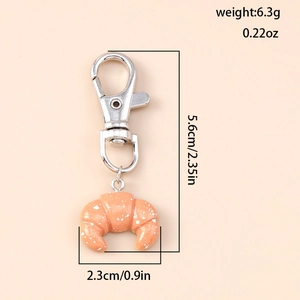 Detail view of croissant keychain with dimensions 2.35 inches showing resin texture