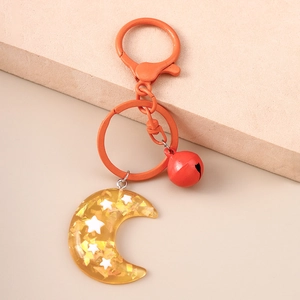 Close-up of golden resin crescent moon keychain with stars and small red bell