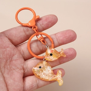Dettaglio portachiavi a forma di delfino in resina arancione con glitter e moschettone in metallo