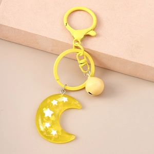 Detail of yellow moon and star resin keychain with matching metal bell and D-ring buckle