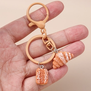 Close-up of realistic faux croissant and bread slices charms on a peach lobster clasp