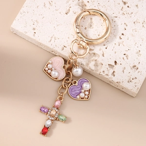 Detail eines Schlüsselanhängers mit Kreuz-Kristallen, Perle und rosa Herz-Anhängern