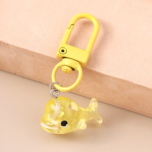 Gros plan d'un porte-clés baleine en résine jaune avec paillettes et fermoir en métal