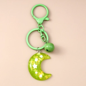 Detail of green resin moon keychain with embedded gold foil, star, and matching bell