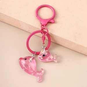 Dettaglio dei ciondoli a forma di delfino in resina rosa con glitter e portachiavi abbinato