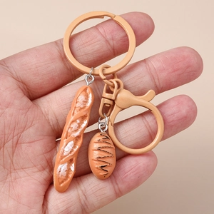 Close-up of realistic resin bread and baguette keychain pendants held in hand