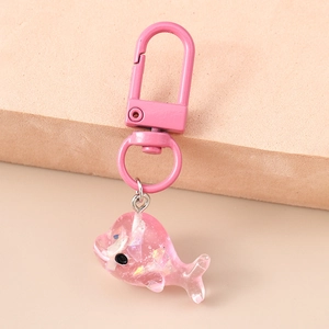 Détail macro d'un porte-clés dauphin en résine rose avec paillettes aurora et mousqueton