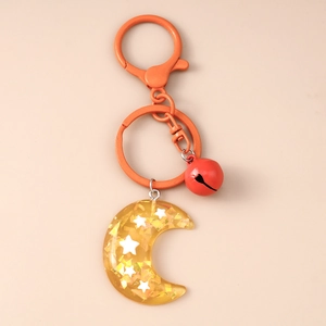 Detail of creative resin moon keychain with star sequins and red bell on orange metal ring