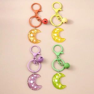 Detail view of resin moon keychains with stars, bells, and lobster clasps in four colors