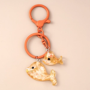 Dettaglio dei portachiavi a forma di delfino in resina gialla con glitter e anello arancione