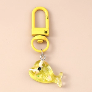 Détail d'un porte-clés baleine en résine jaune translucide avec des paillettes laser