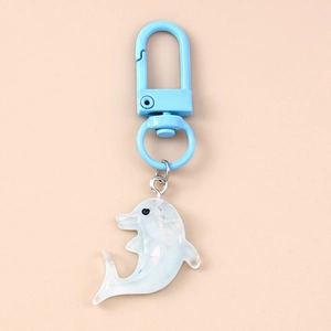 Détail d'un pendentif dauphin nacré avec un anneau bleu clair sur fond beige neutre