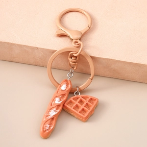 Macro shot of realistic miniature baguette and waffle slice on a metal keychain ring