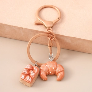 Close-up of realistic faux bread croissants and woven bread keychains with rose gold hardware