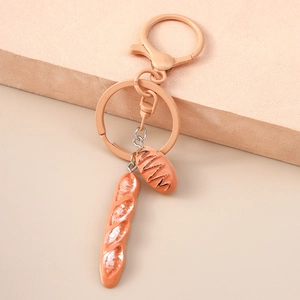 Macro shot of realistic baguette and pastry charms on a stylish caramel keychain