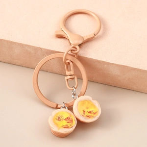 Macro shot of realistic resin egg pendant keychain with champagne gold metal clip