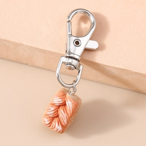 Macro shot of a creative braided bread keychain with realistic texture on a beige display block