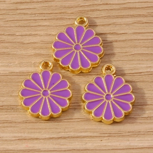Détail de breloques marguerites violettes avec bords dorés sur fond de bois clair