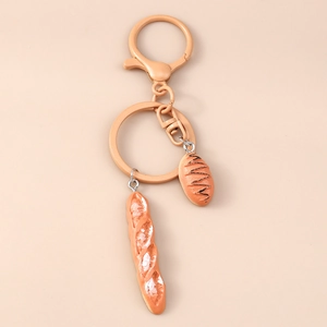 Detailed view of realistic French baguette and pastry charms with orange-coated keychain ring