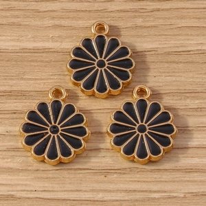 Détail macro de trois pendentifs fleur en émail noir et métal doré pour la création de bijoux