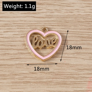 Detailed macro view of an 18mm heart-shaped golden pendant with pink enamel and love text