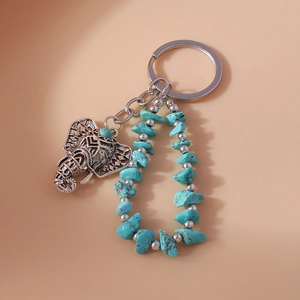 Detail of bohemian silver elephant keychain with turquoise stones and hollow carving