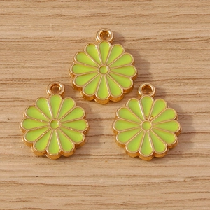 Trois breloques de marguerites jaune-vert avec monture dorée sur un support en bois