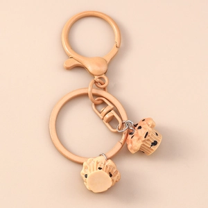 Macro detail of realistic muffin cake keychains with metallic clasp on peach background