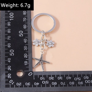 Macro shot of a vintage silver alloy starfish and flower keychain with size ruler scale