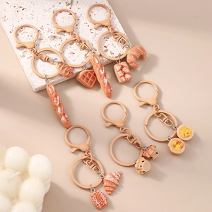 Close-up of assorted realistic resin bread and pastry keychains with matte gold rings