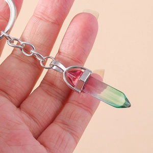 Close-up of a gradient crystal hexagonal pendant keychain held by hand on pink background