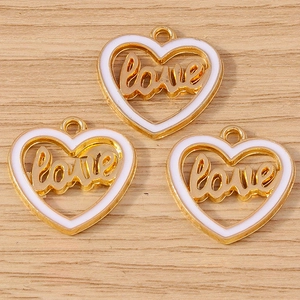 Detail of three golden heart pendants with white enamel and cursive love lettering