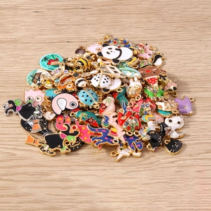 Collection of colorful enamel animal charms with gold bases on a wood background