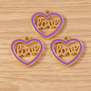 Three purple enamel heart pendants with gold frames and love engraving on wood