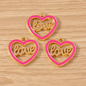Close-up of three pink heart charms with golden Love lettering for DIY jewelry making