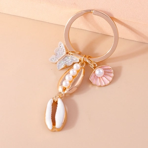 Detail of champagne gold ocean keychain featuring glitter butterfly and pearl shells