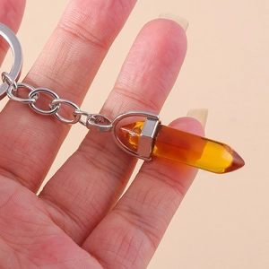 Macro view of amber hexagonal crystal pendant keychain held in hand for size display