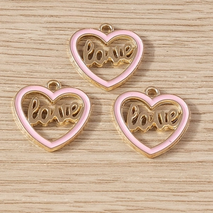 Close-up of heart-shaped pink enamel pendants with gold Love lettering for jewelry DIY