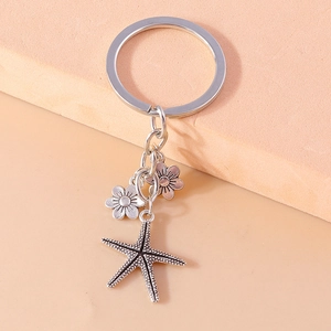 Detailed close-up of a silver mermaid starfish keychain with floral charms and metal ring