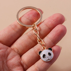 Detail eines lila Panda-Schlüsselanhängers mit goldenem Ring in der Hand gehalten