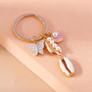 Close-up of golden mermaid keychain with resin butterfly and pearl shell charms