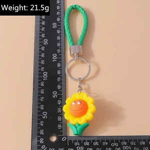 Détail du porte-clés tournesol avec pétales en silicone, sangle verte et échelle de mesure 15cm