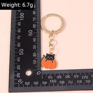 Detail of Halloween black cat in pumpkin keychain with alloy dripping oil finish