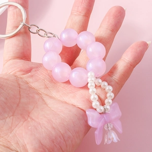 Detail of beaded keychain with pink pearls, purple frosted bow and lily of the valley charm